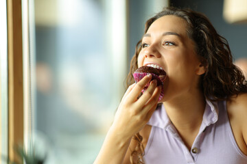 Woman eating chocolate cupcake in a restaurant