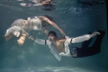 Obraz na płótnie Canvas fashionable man in a white shirt and a woman in a white dress underwater in the pool