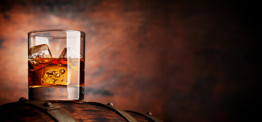 Glass of whiskey with ice cubes on the old barrel