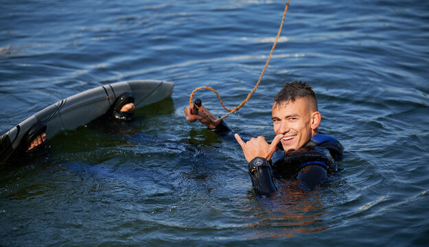 Portrait of wakeboarder surfing on lake. Happy man surfer having fun wakeboarding in the cable park. Water sport, outdoor activity concept.
