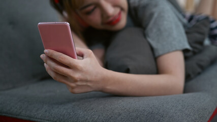 Cropped shot of woman lying on couch and using mobile phone, spending leisure weekend time at home