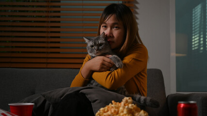 Young asian woman with her lovely cat watching TV at home. Leisure activity, relaxation, hobby concept