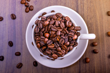 International coffee day concept.Bowl overflowing with coffee beans on wooden table. Aerial view.