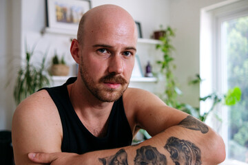 Man with mustache and tattoo at home