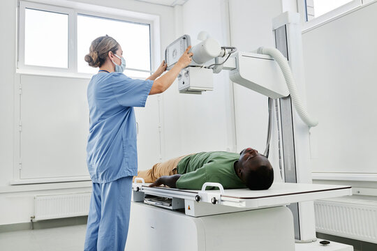 Nurse adjusting X-ray machine for patient in clinic