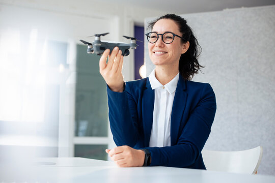 Smiling businesswoman with eyeglasses examining drone