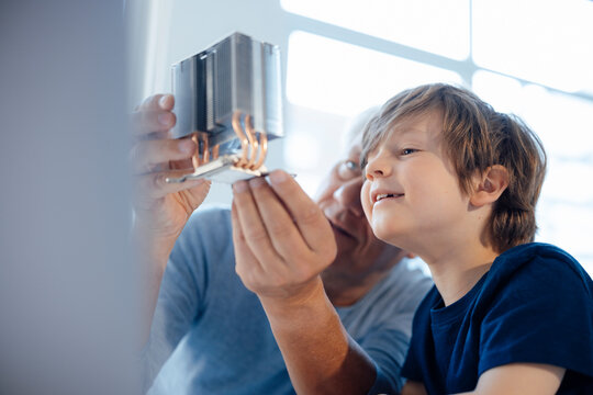 Grandfather examining model object by grandson at home