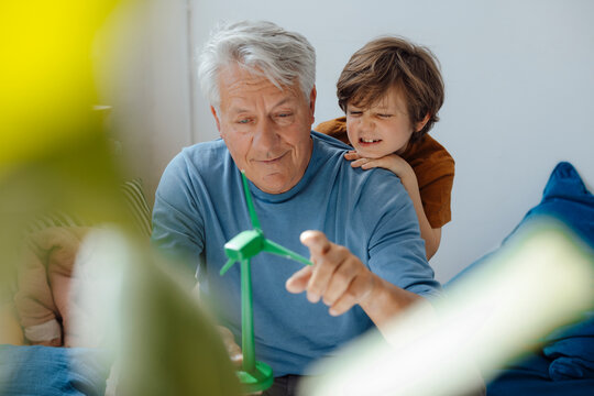 Grandfather and grandson examining wind turbine model at home