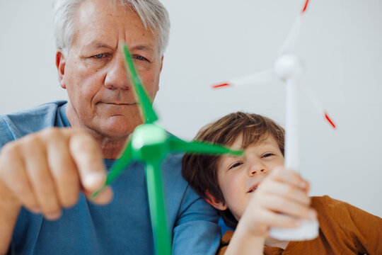 Grandfather and grandson analyzing wind turbine models at home