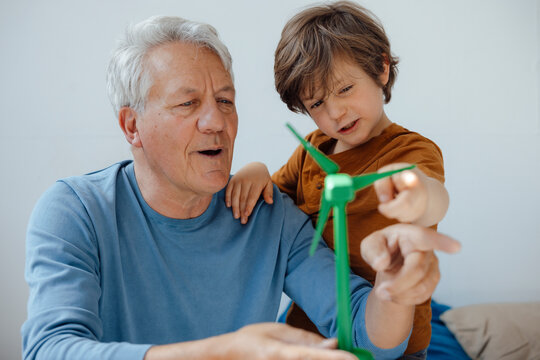 Grandfather and grandson analyzing wind turbine model at home