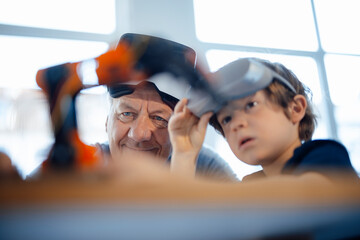 Grandson and grandfather examining robot model at home