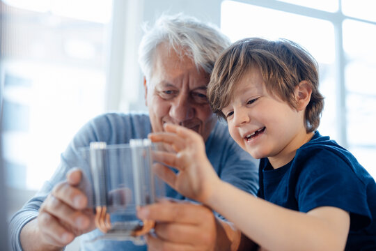 Smiling grandson and grandfather examining heating module at home