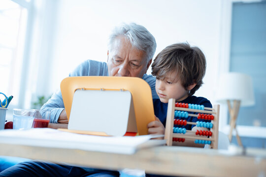 Senior man and boy using tablet PC at home
