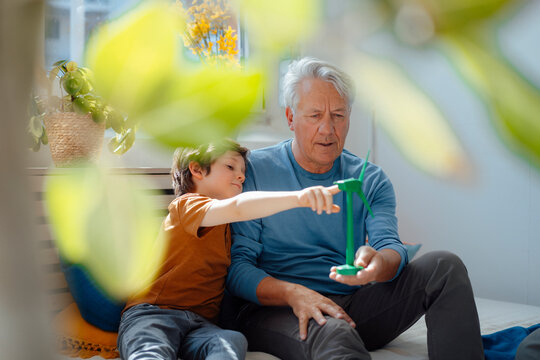Grandfather and grandson examining wind turbine model at home
