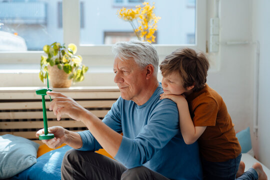 Grandfather analyzing wind turbine model by grandson at home