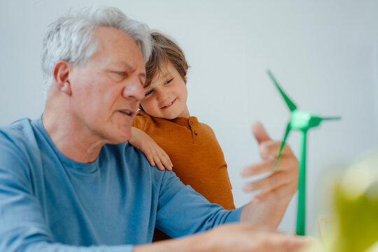 Grandfather and grandson analyzing wind turbine model at home