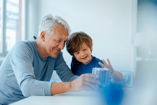 Smiling senior man and grandson examining heating module at home