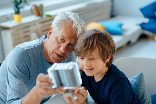 Grandson and grandfather analyzing heating module in living room