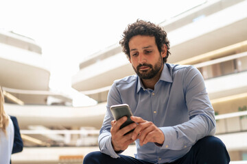 Businessman text messaging through mobile phone in office