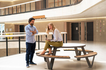 Businesswoman laughing with colleague in office corridor