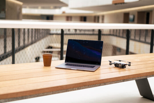 Laptop and drone with coffee cup on table at office