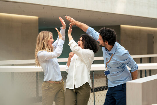Happy business colleagues giving high-five in corridor