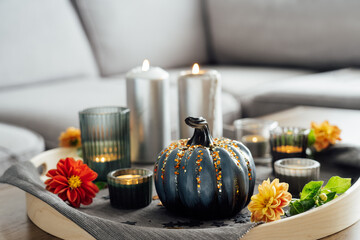Autumn cozy mood composition for hygge home decor. Gray pumpkin with sequins, candles and fresh...