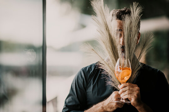 Man having drink covering face with pampas grass