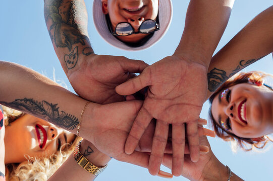 Friends stacking hands on sunny day