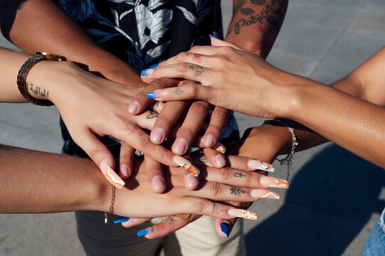 Hand's of friends stacked together on sunny day