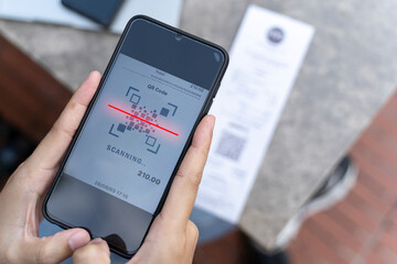 Hands of young woman using mobile smart phone for scan and payment online with family budget cost bills on desk in home office