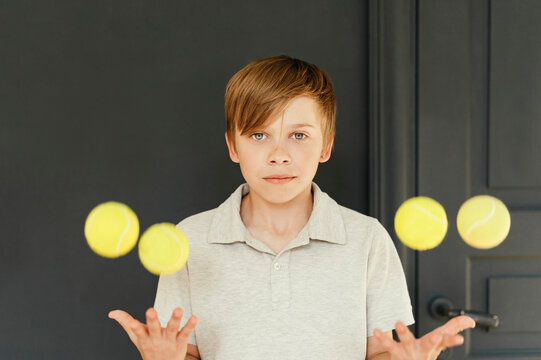 Boy juggling tennis balls at home