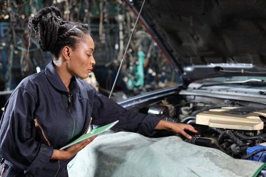 Woman technician car mechanic in uniform checking maintenance a car service with tablet at repair garage station. .Car repair service concept
