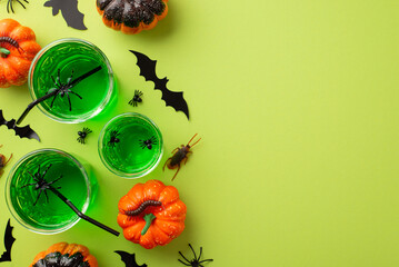 Halloween party drinks concept. Top view photo of green punch with floating spiders in glasses bat...
