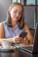 Female freelancer using smartphone in cafe