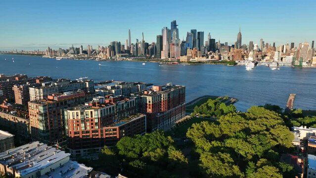 Midtown Manhattan skyline. Aerial pullback reveals Hoboken NJ. Summer golden hour light.