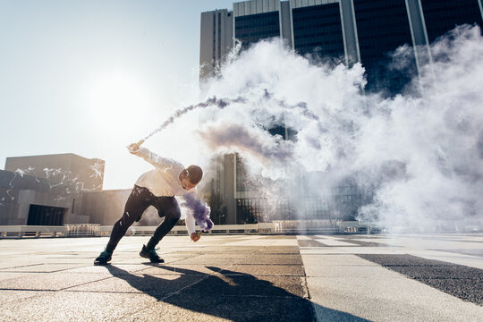 Man practicing free running with a smoke grenade - Powered by Adobe
