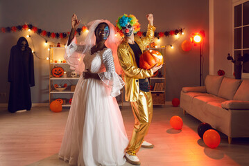 Two happy adult multiracial friends dressed up in spooky Halloween outfits of Dead Bride and Crazy...