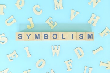Symbolism figure of speech concept in English grammar class lesson. Wooden blocks typography flat lay in blue background.	