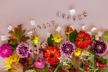 a festive card, wallpaper, an autumn background of colorful cut garden flowers. floral concept. text made of wooden letters - hello autumn.