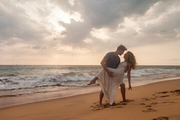 Fototapeta na wymiar Happy couple together french kissing on tropical sandy beach at sea sunset background. Beauty couple enjoying honeymoon summer at ocean coastline. Lovely man and woman relaxing happiness. Copy space