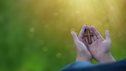 Man praying with cross in nature sunrise background, Symbol of Faith. Religious young man praying...