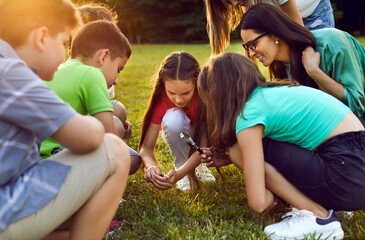 Curious school children explore nature and make little discoveries together. Group of happy...