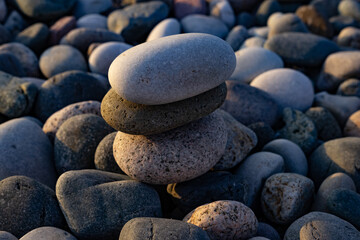 Stacked stones on a beach. Large tower of stones background of small pebbles. Serenity and calmness. Recreation concept