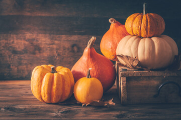 Rustic autumn still life with pumpkins and golden leaves on a wooden surface - obrazy, fototapety, plakaty