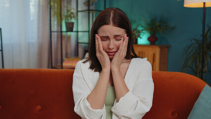 Upset disappointed caucasian young woman wipes tears and cries from despair, being sad because of...
