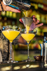 man hand bartender pouring cocktail in glass on the bar counter