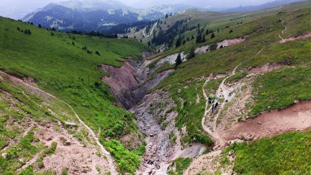 Mountain landscape of canyon between slanted green hills, descending drone flight