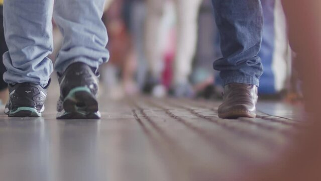 Unrecognizable crowd of people's feet walking in casual wear indoors. Slow motion