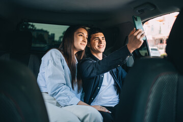 Loving couple travelling in the backseat of a cab. Smiling man and woman going out in a taxi.